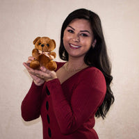 A beautiful woman holds a brown teddy bear
