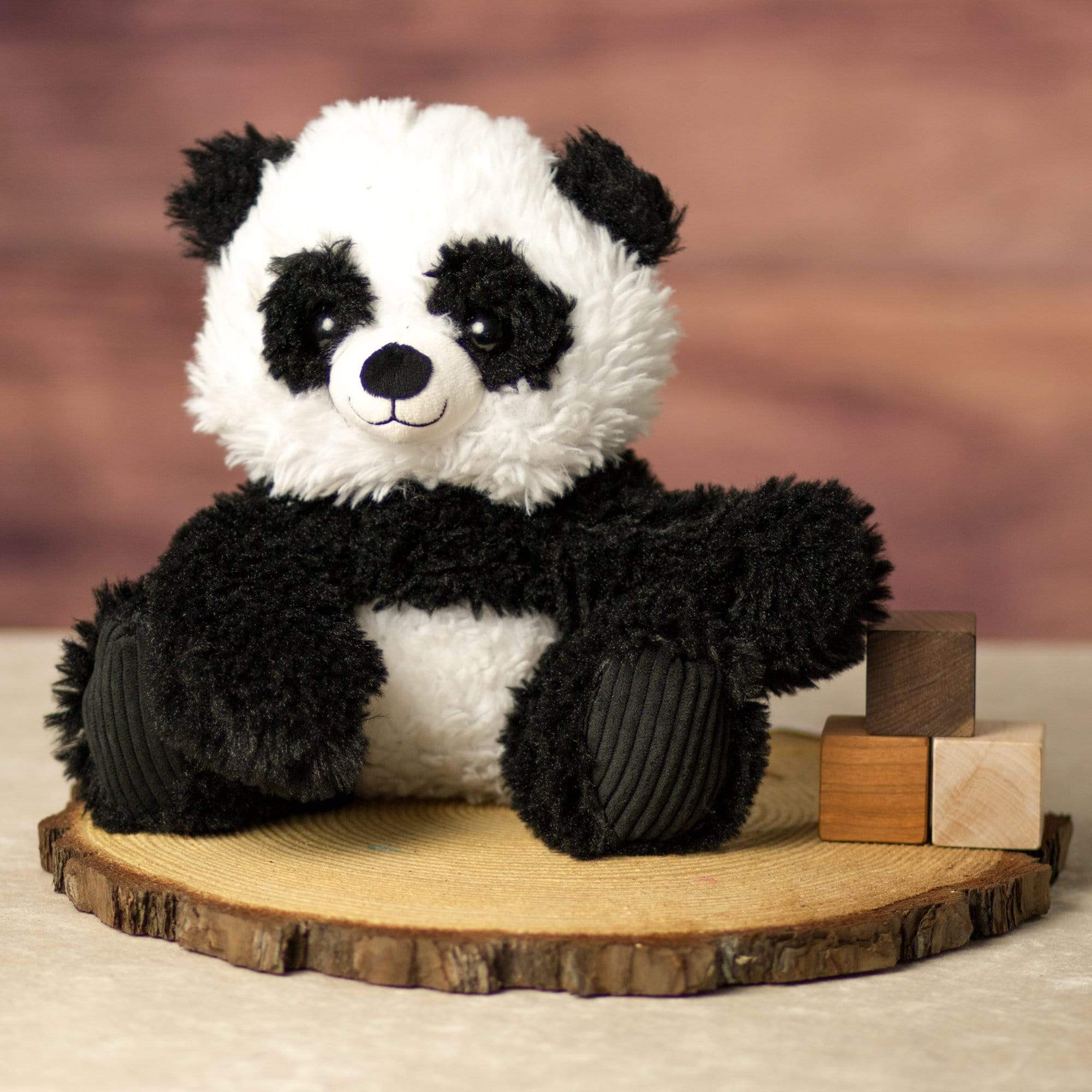 A scruffy black and white panda that is 9.5 inches tall while sitting on top of a piece of wood