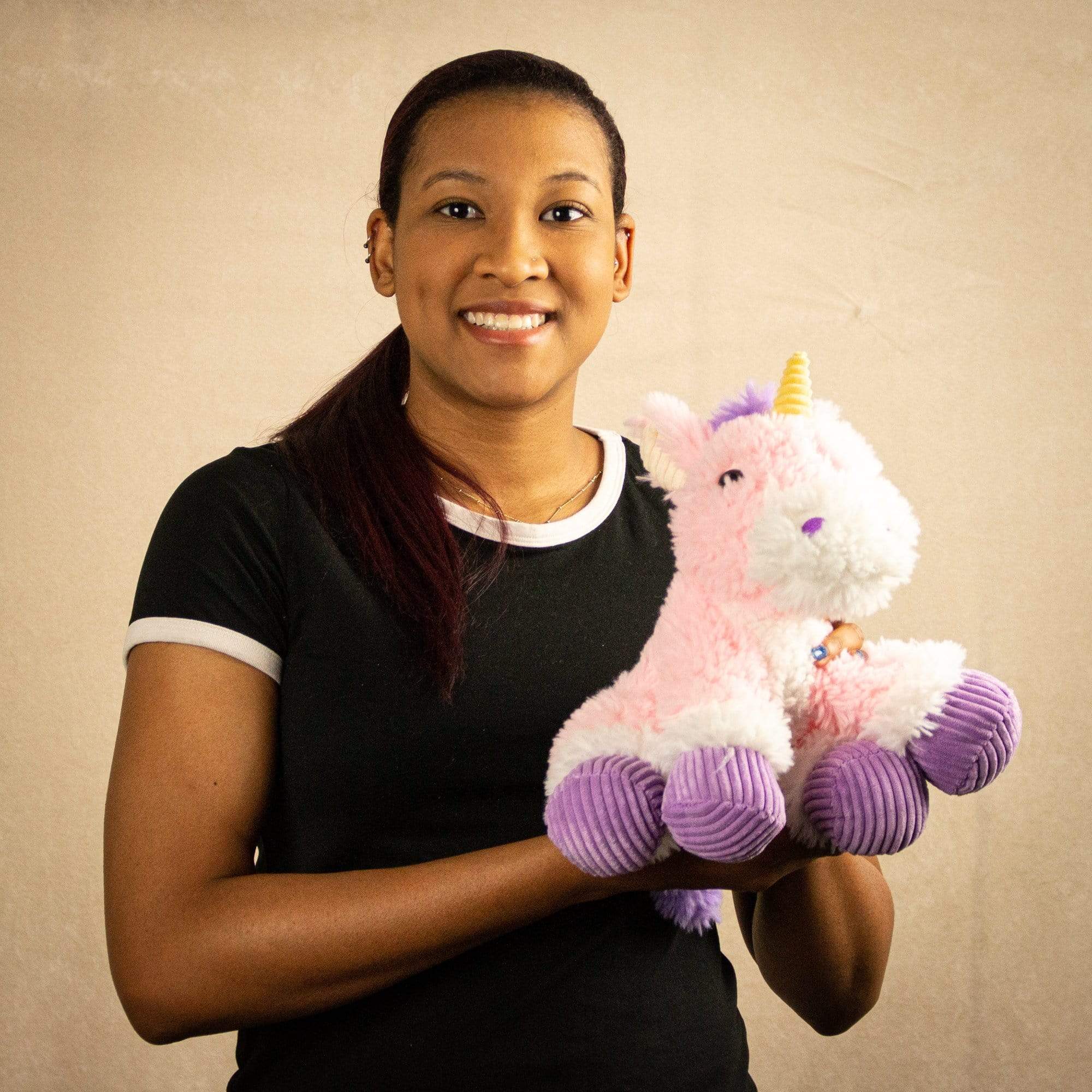 A woman holds a scruffy pink unicorn that is 9.5 inches tall while sitting