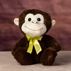 A brown monkey that is 10 inches tall with a beige face, ears, and wears a yellow bow tie