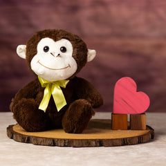 A brown monkey that is 10 inches tall with a beige face, ears, and wears a yellow bow tie next to wooden blocks