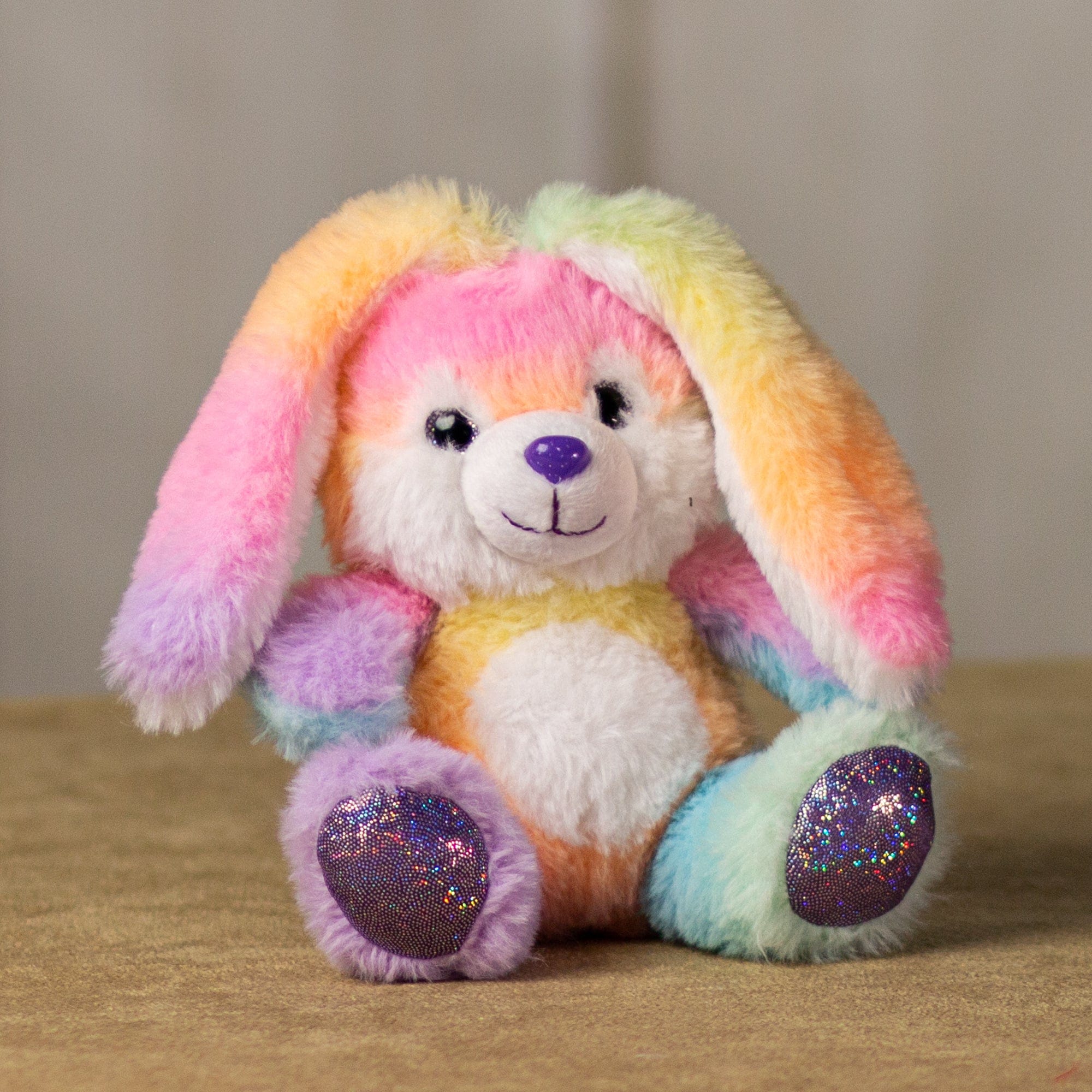 A rainbow bunny that is 6 inches tall while sitting with shiny feet and nose