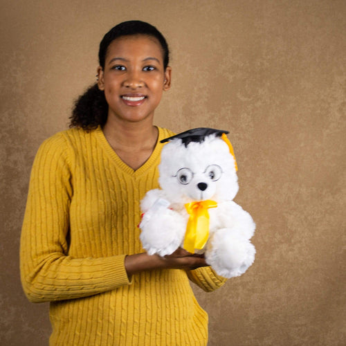 A woman holds a white grad bear that is 10 inches tall while standing