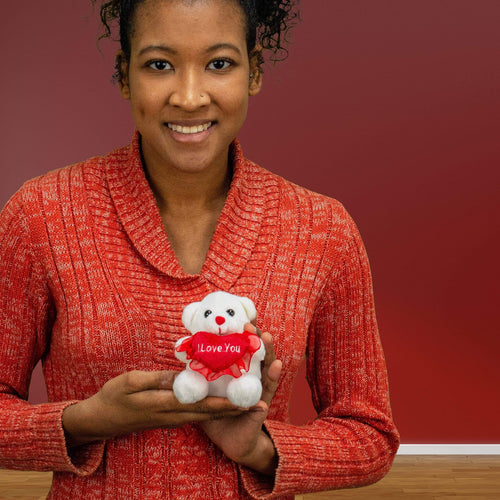 A woman holds a white bear that is 4 inches tall while sitting holding a red I LOVE YOU heart