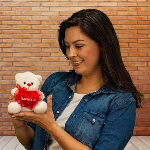 A woman holds a white bear that is 6 inches tall while sitting holding a red heart that says, "I Love You"