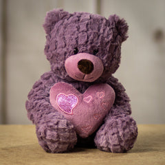 A purple bear that is 10 inches tail while sitting holding a heart accented with smaller shiny hearts