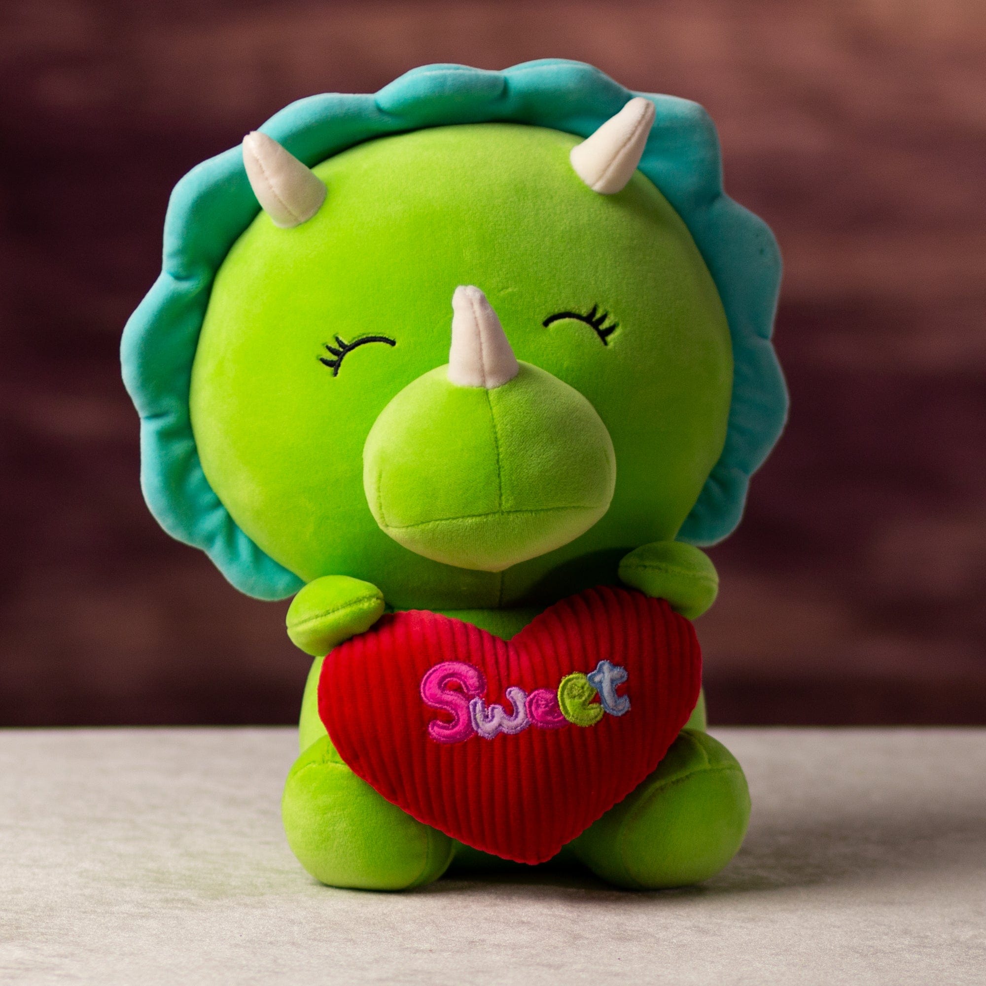 A green dinosaur that is 10.5 inches tall while sitting holding valentine heart