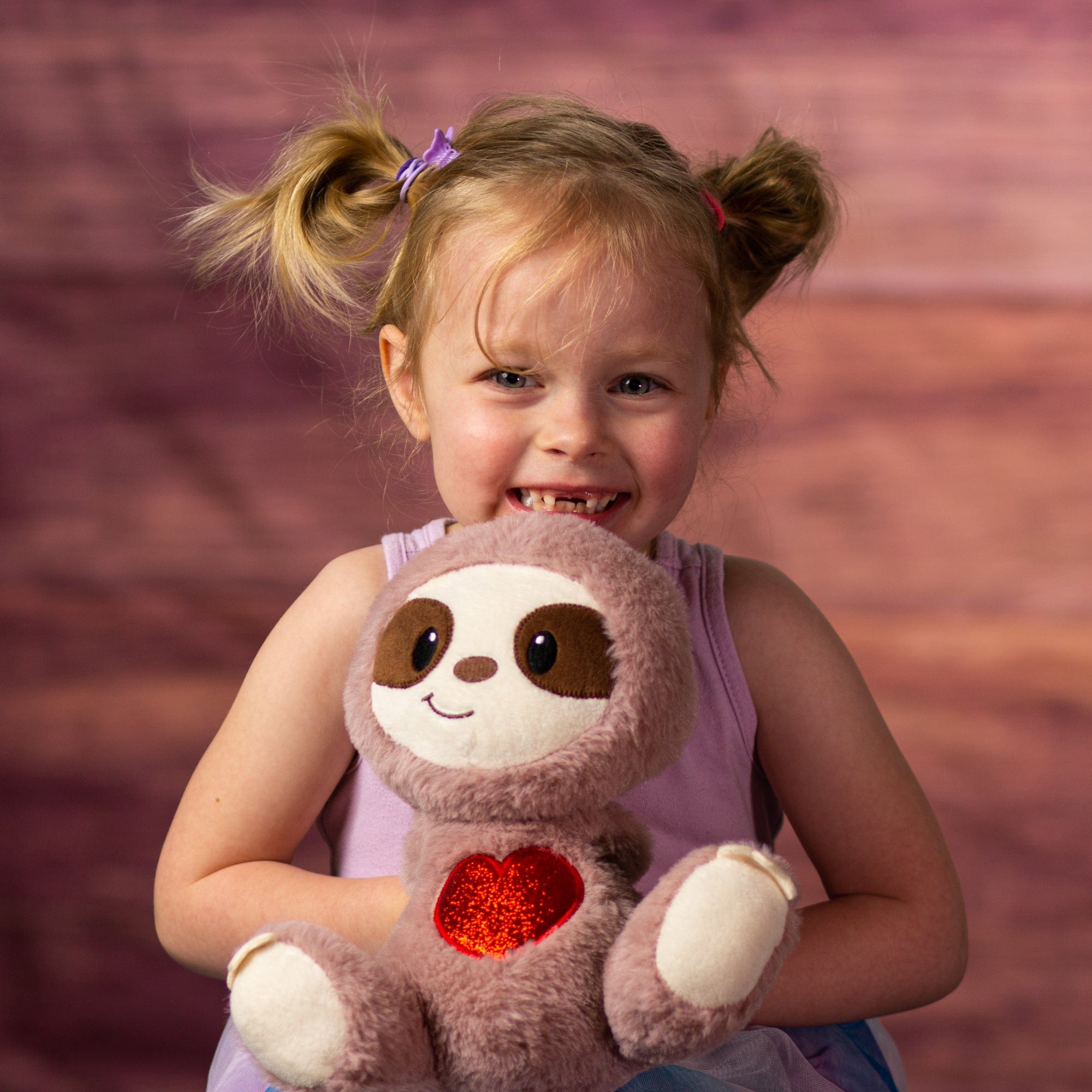 girl holding 9 in valentines sloth with a glitter heart on stomach