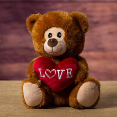 A brown bear that is 9.5 inches tall while sitting holding a red Love bear