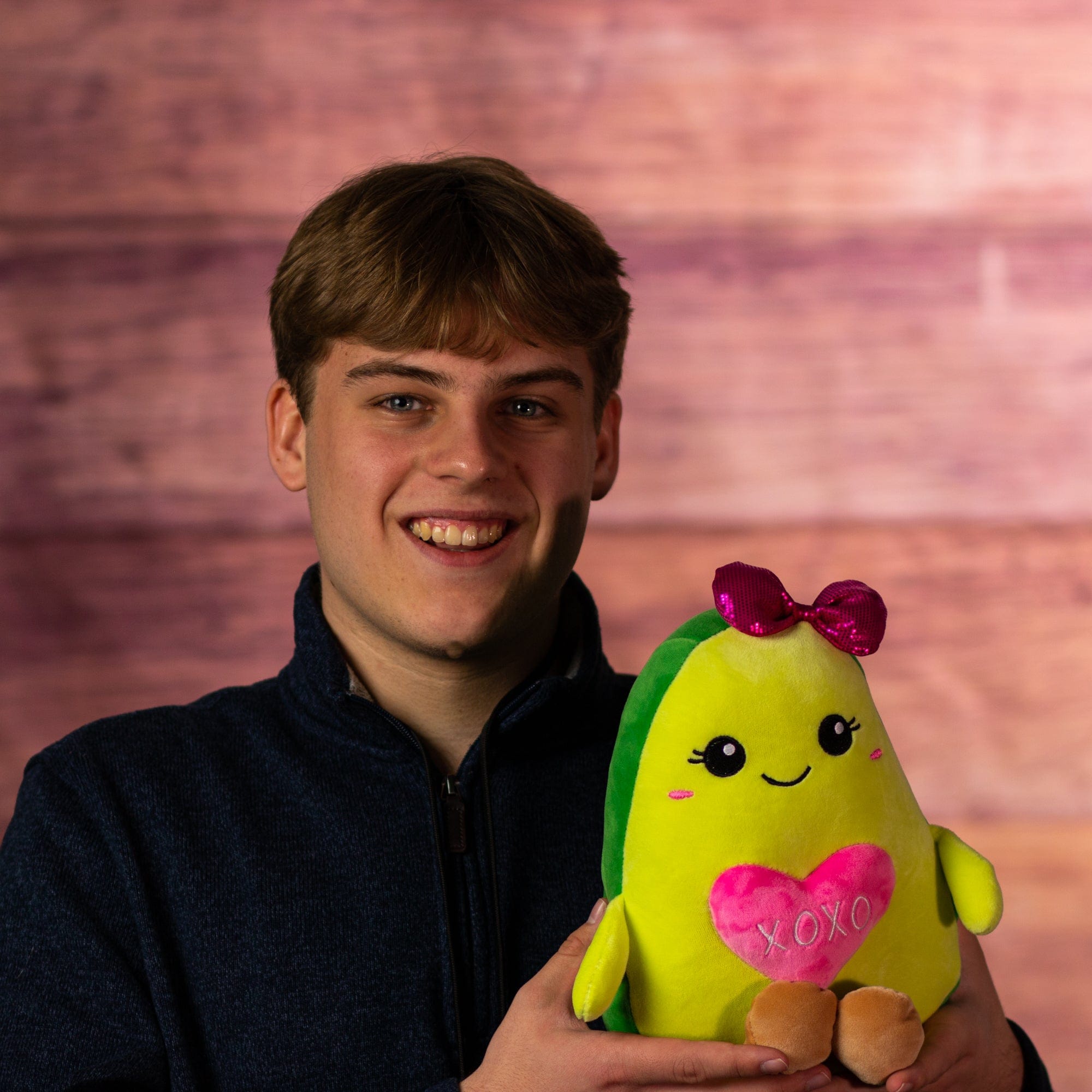 boy holding 9 in stuffed valentines avocado holding a heart