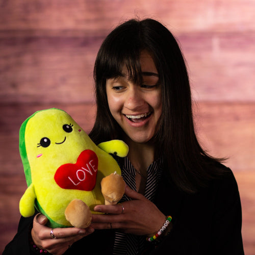 girl holding 9 in stuffed valentines avocado holding a heart